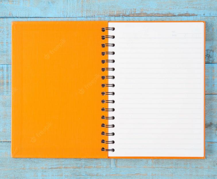 Caderno com capa laranja sob uma mesa cinza aberto.